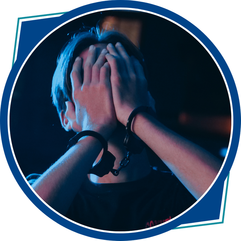 young person with handcuffs and hands over face in anguish